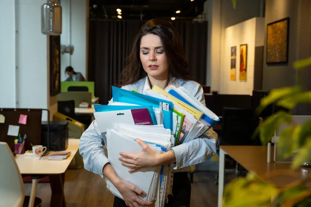 femme portant beaucoup de contrats d'assurance professionnelle, elle doit faire le tri